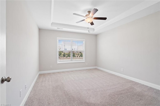 empty room featuring a raised ceiling, ceiling fan, and carpet flooring