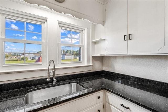 kitchen featuring sink, white cabinetry, and dark stone countertops