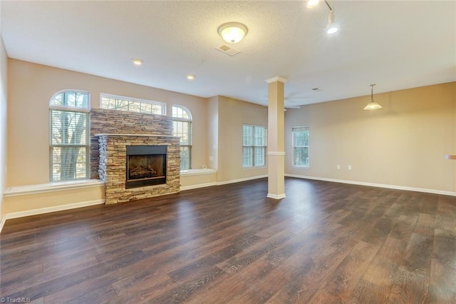 unfurnished living room with a textured ceiling, dark hardwood / wood-style floors, and a stone fireplace