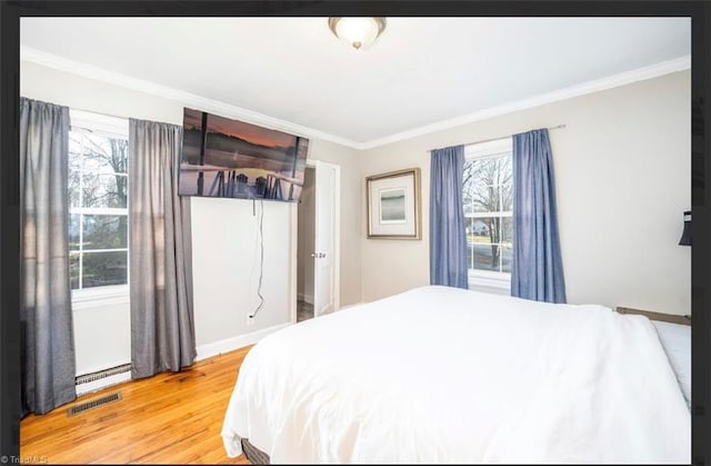 bedroom with visible vents, light wood-style flooring, crown molding, and a baseboard radiator