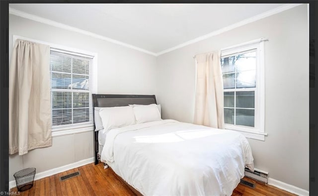 bedroom with crown molding, baseboards, and wood finished floors