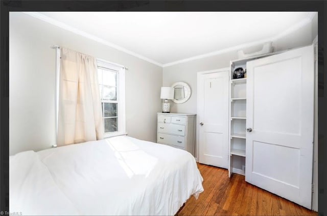 bedroom featuring a closet, wood finished floors, and ornamental molding