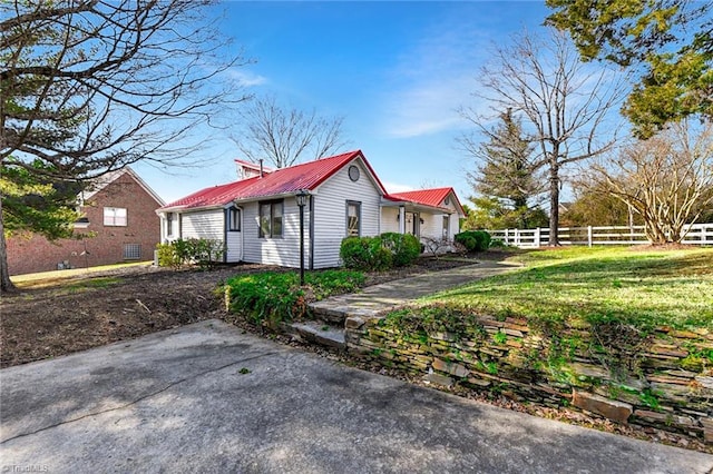 view of property exterior with metal roof, a yard, and fence