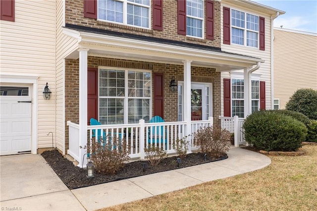 view of exterior entry featuring brick siding, a porch, and a garage