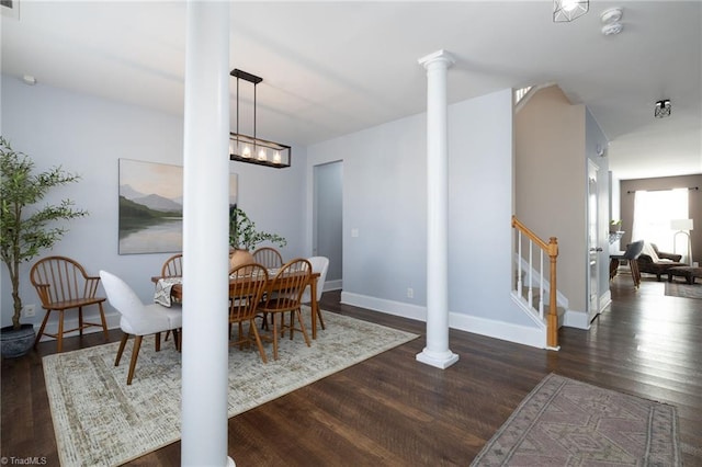 dining room with wood finished floors, baseboards, ornate columns, stairs, and a chandelier