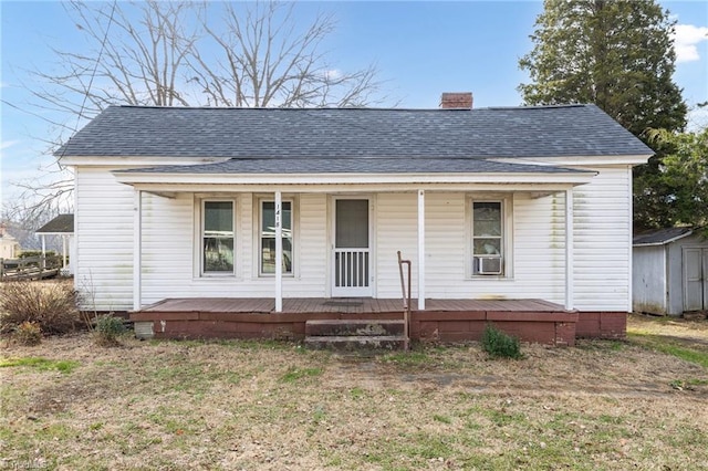 view of front of home with a porch, a front lawn, and a storage unit