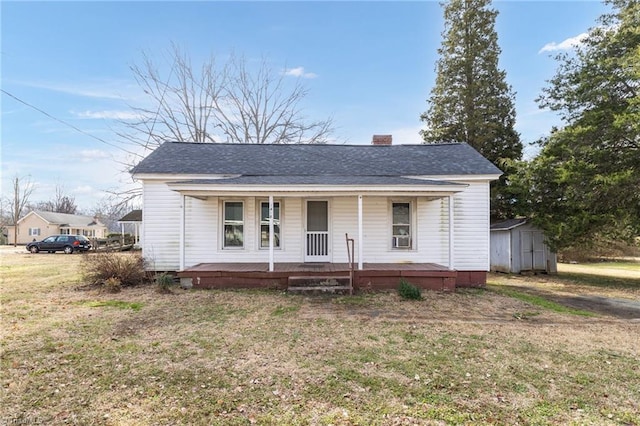 view of front of property featuring a storage shed, a front yard, and a porch