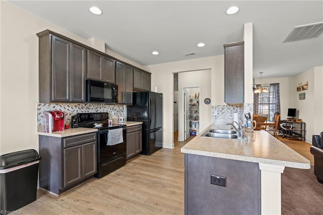 kitchen featuring kitchen peninsula, sink, black appliances, decorative light fixtures, and a notable chandelier