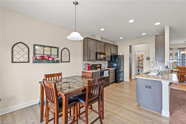 dining area with light hardwood / wood-style flooring, a chandelier, and sink