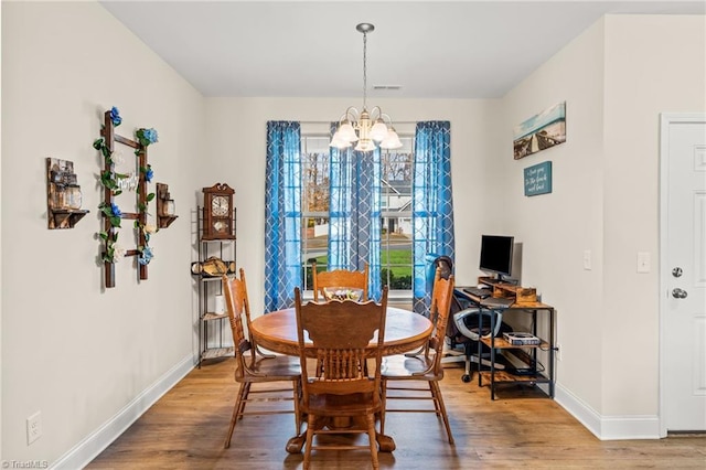 dining space with wood-type flooring and a notable chandelier