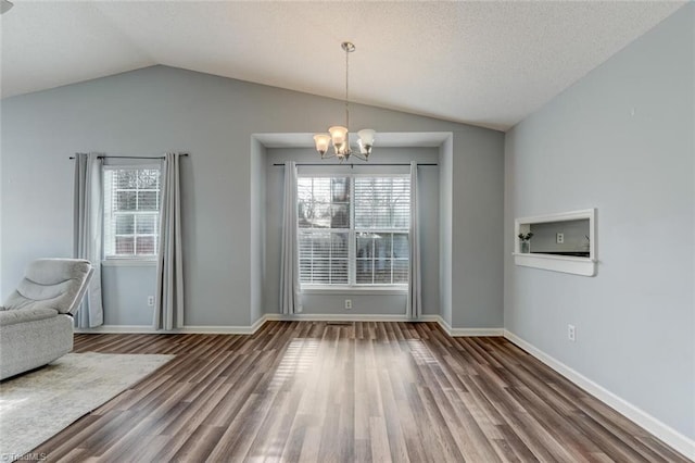 unfurnished dining area featuring a notable chandelier, dark hardwood / wood-style flooring, a textured ceiling, and vaulted ceiling