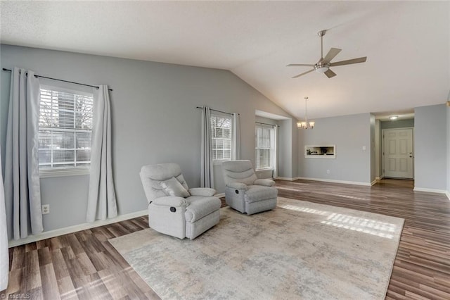 living area with hardwood / wood-style floors, ceiling fan with notable chandelier, and lofted ceiling