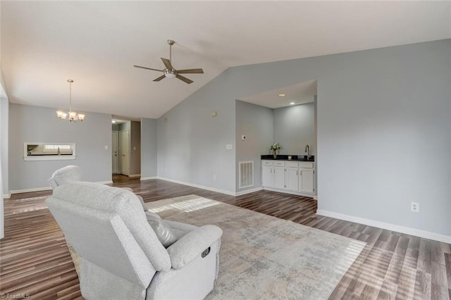 living room featuring ceiling fan with notable chandelier, wood-type flooring, sink, and vaulted ceiling