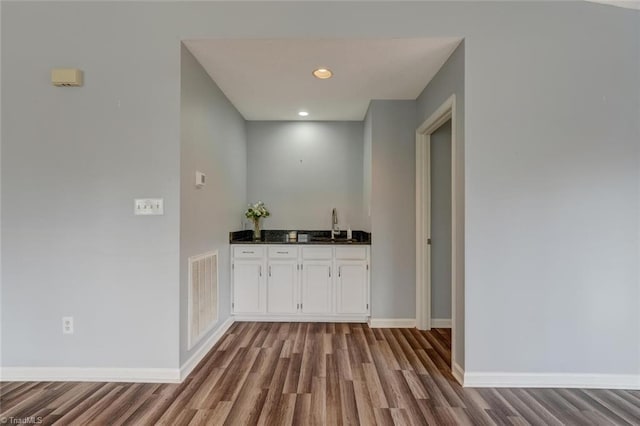 bar with sink, white cabinets, and light wood-type flooring