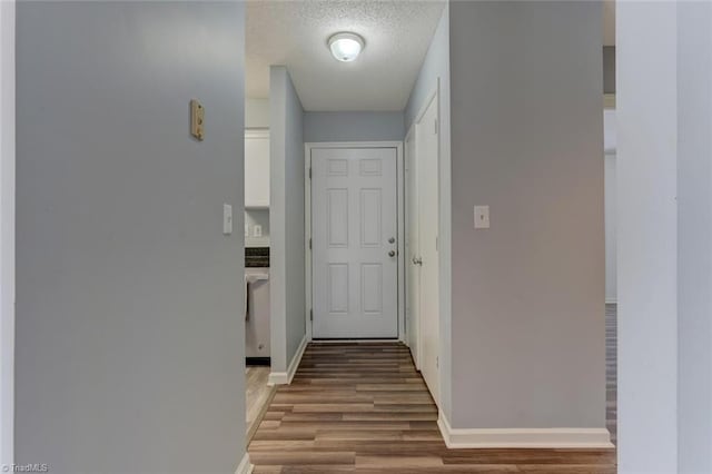 hallway with a textured ceiling and hardwood / wood-style flooring