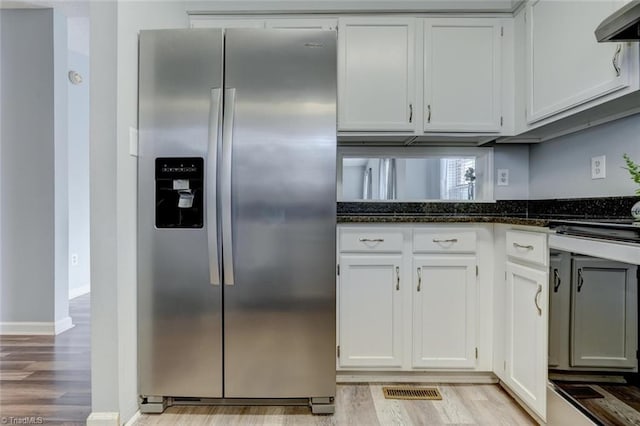 kitchen with white cabinets, ventilation hood, stainless steel refrigerator with ice dispenser, light hardwood / wood-style flooring, and dark stone countertops