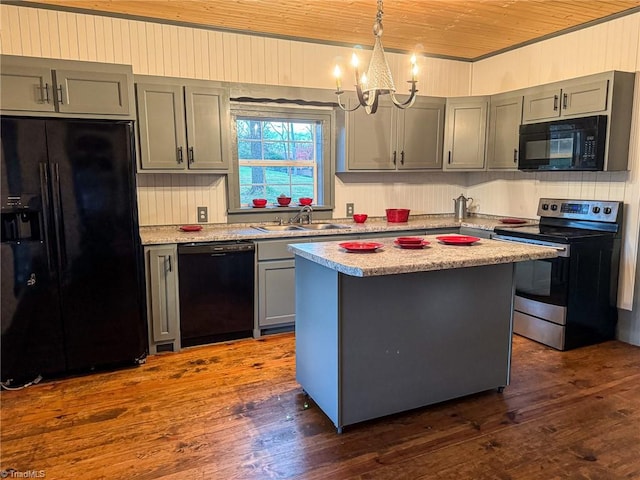 kitchen with black appliances, sink, a notable chandelier, a kitchen island, and dark hardwood / wood-style flooring