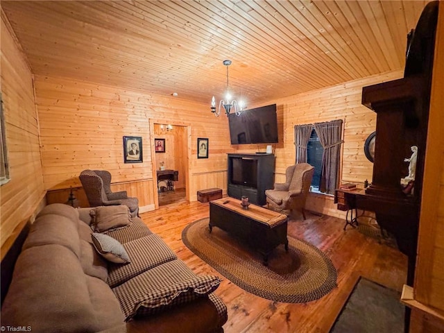 living room with a chandelier, light hardwood / wood-style floors, wooden ceiling, and wood walls