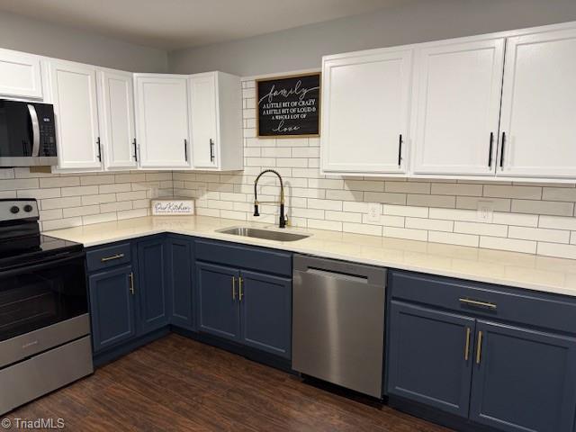 kitchen featuring appliances with stainless steel finishes, tasteful backsplash, sink, dark hardwood / wood-style floors, and white cabinetry