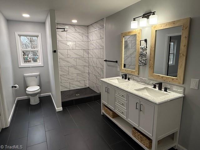 bathroom featuring tile patterned flooring, vanity, toilet, and tiled shower