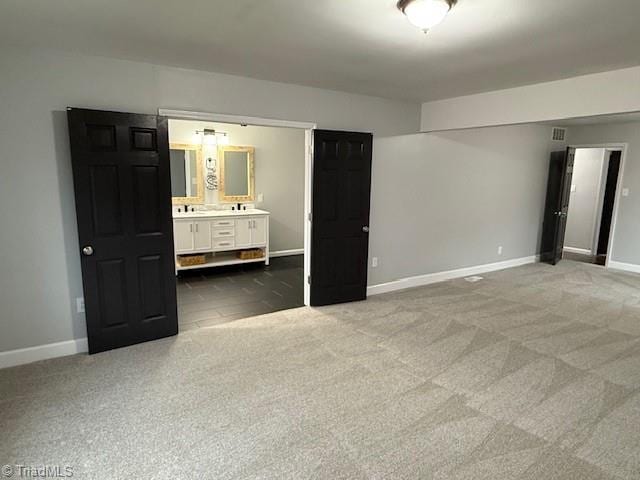 unfurnished bedroom featuring connected bathroom and carpet floors