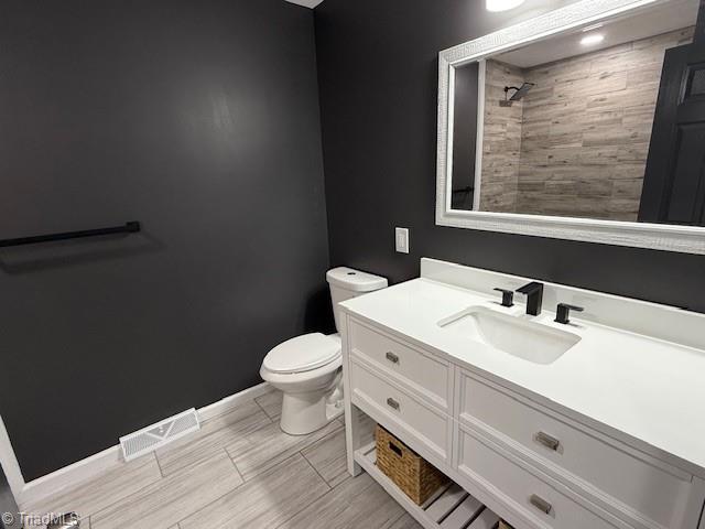 bathroom with tiled shower, vanity, and toilet