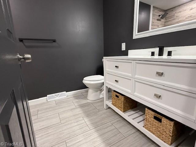 bathroom with tiled shower, vanity, and toilet