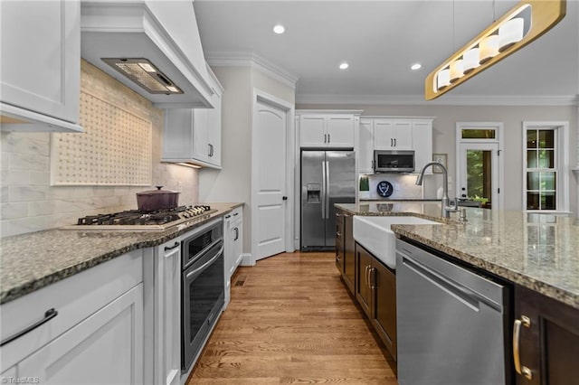 8441 Alice Player Dr, Oak Ridge, NC 27310 - kitchen featuring stainless steel appliances, a sink, premium range hood, ornamental molding, and white cabinets