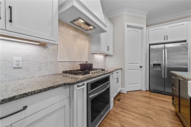 8441 Alice Player Dr, Oak Ridge, NC 27310 - kitchen featuring appliances with stainless steel finishes, premium range hood, crown molding, white cabinetry, and dark stone counters