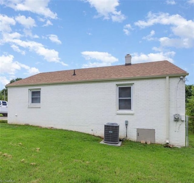 view of side of property with central AC unit and a lawn