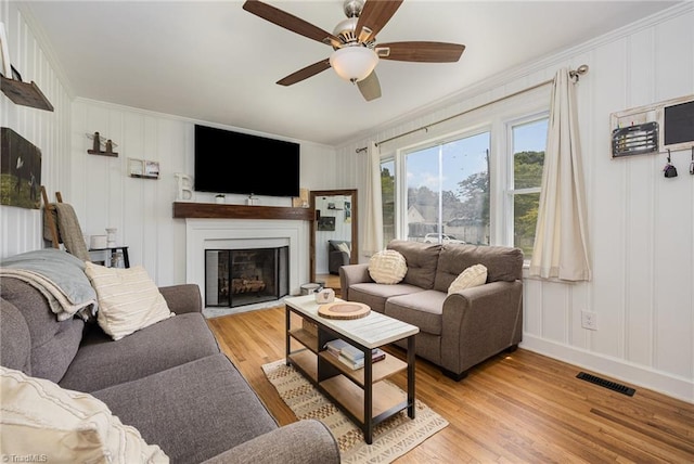 living room featuring ceiling fan, crown molding, and light hardwood / wood-style flooring