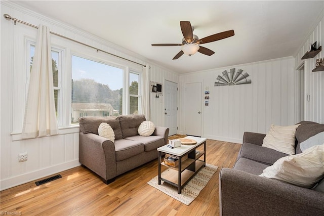 living room with light hardwood / wood-style floors, crown molding, and ceiling fan