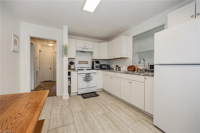 kitchen with dark stone counters, white appliances, white cabinets, sink, and light hardwood / wood-style floors