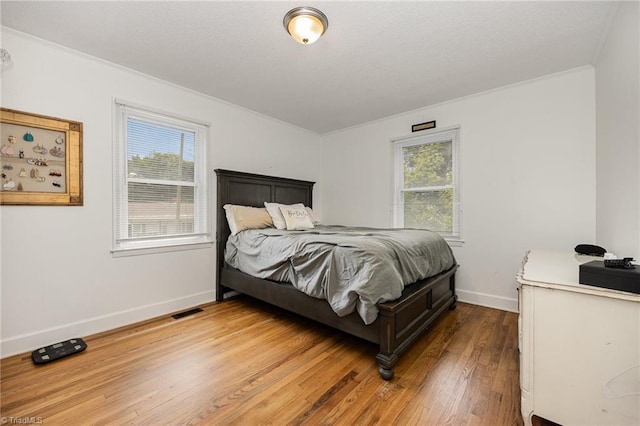 bedroom with ornamental molding and wood-type flooring