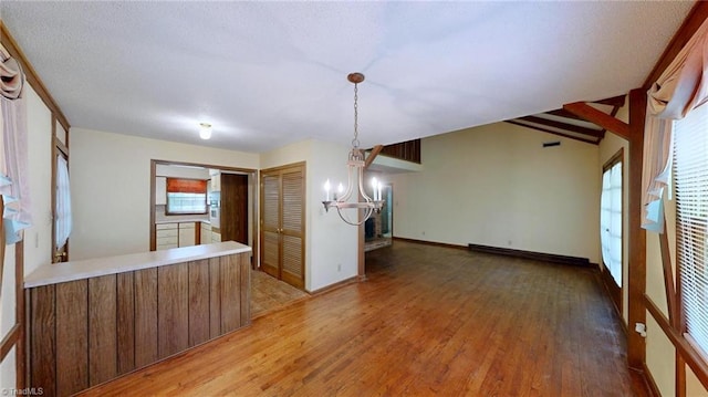 interior space featuring a baseboard heating unit, light wood-style floors, baseboards, and a notable chandelier