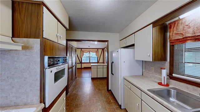 kitchen featuring white cabinetry, a sink, white appliances, and light countertops