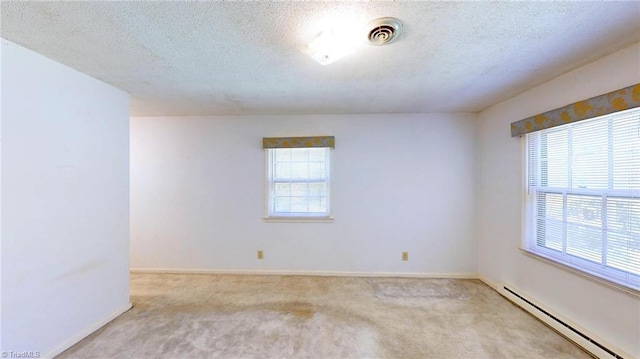 carpeted empty room featuring a baseboard heating unit, baseboards, a textured ceiling, and visible vents