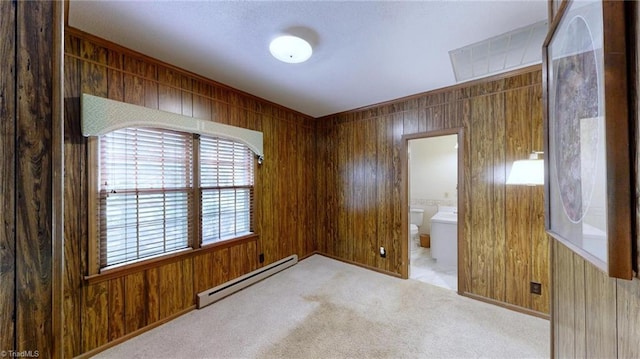 spare room with a baseboard radiator, carpet floors, visible vents, and wooden walls