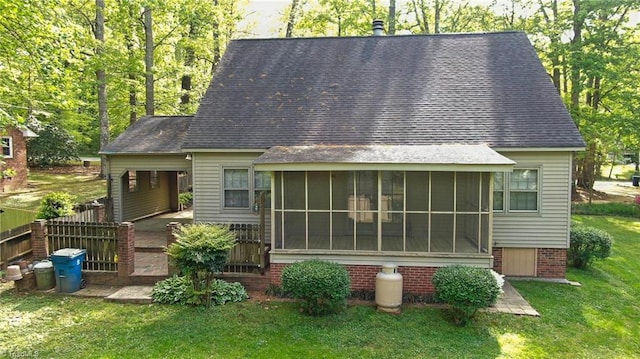 back of house with fence, a sunroom, a yard, and roof with shingles