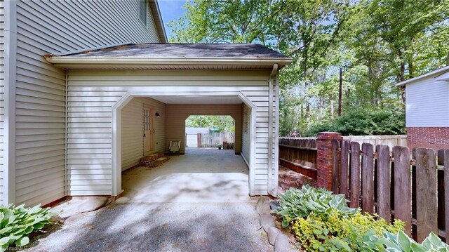 view of parking / parking lot featuring fence and concrete driveway