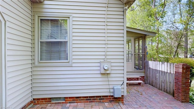 view of property exterior with a patio area, a sunroom, and fence
