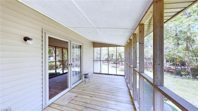 unfurnished sunroom featuring hardwood / wood-style floors, wood walls, and french doors