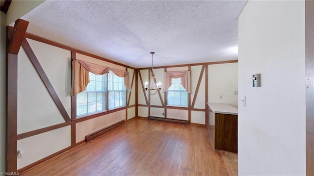 unfurnished dining area with a baseboard heating unit, plenty of natural light, and wood finished floors