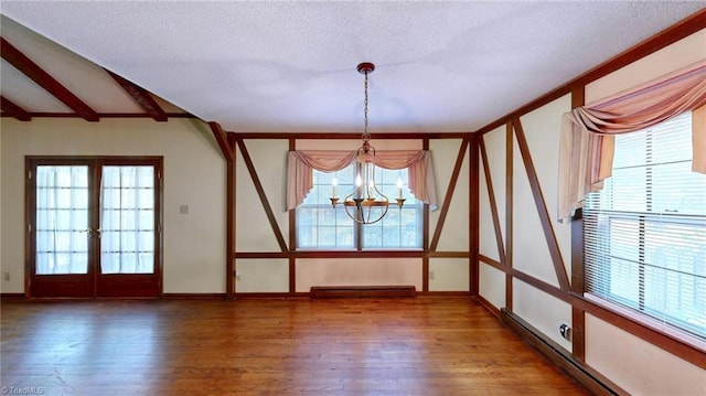 unfurnished room featuring a baseboard heating unit, wood-type flooring, an inviting chandelier, and plenty of natural light