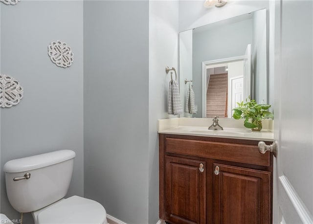 bathroom featuring toilet, vanity, and baseboards