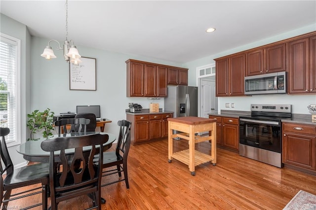 kitchen with appliances with stainless steel finishes, a chandelier, light wood finished floors, dark countertops, and recessed lighting