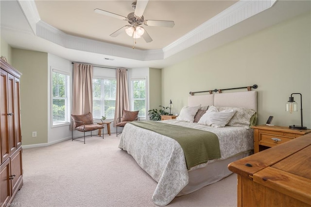 bedroom with a raised ceiling, multiple windows, light carpet, baseboards, and crown molding
