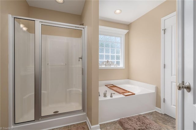 bathroom with a stall shower, a garden tub, and baseboards