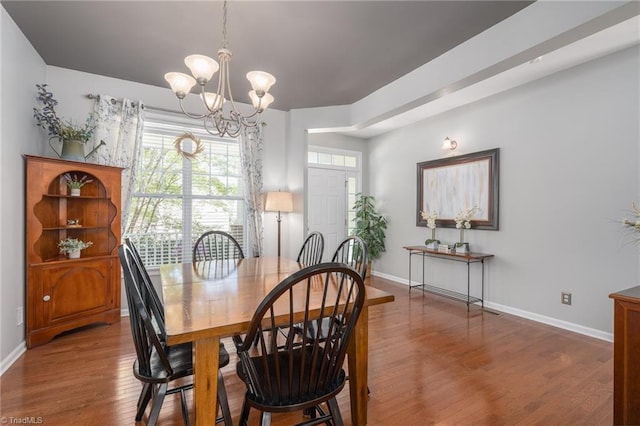 dining area with a chandelier, wood finished floors, and baseboards