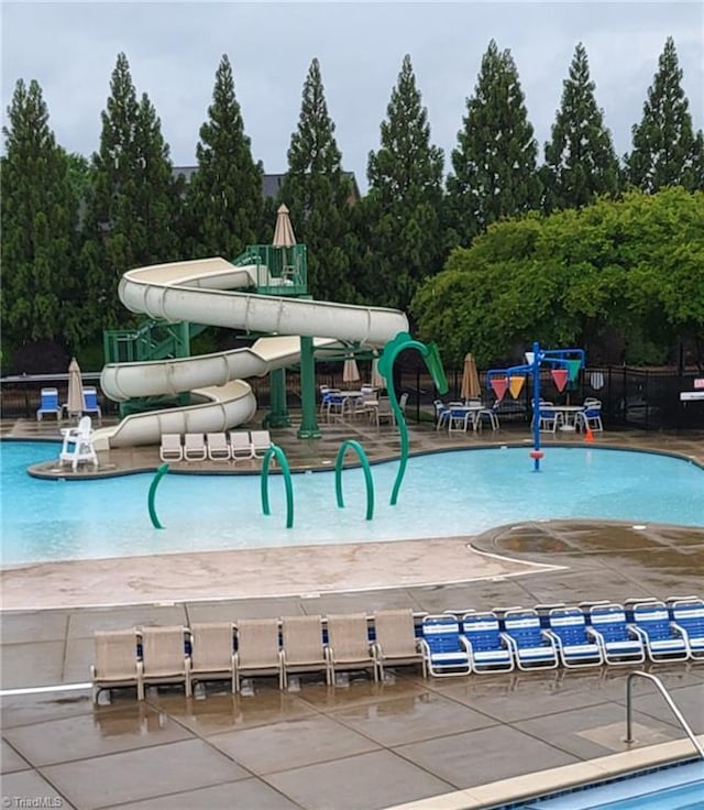 community pool with a water slide and fence